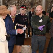 King Charles and Queen Consort Camilla are shown an exhibit at Colchester Castle by curator Glynn Davis