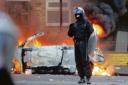 In the thick of it - a lone police officer stands near a torched car