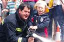 In the line of fire - four-year-old Finley Brett gives leading firefighter Trevor Hearn a hand with the hose. Picture: ROB SAMBROOK (56831-5)