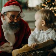 Santa attends to a child at his grotto. Credit: Pexels