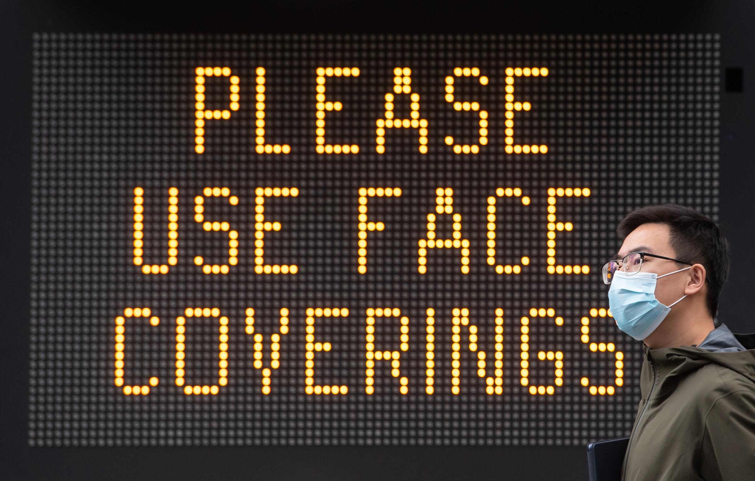 PA REVIEW OF THE YEAR 2020 .File photo dated 09/06/20 of a man wearing a protective face mask walking past signage advising the use of face coverings, near Tower Bridge, London, following the introduction of measures to bring England out of lockdown. PA 