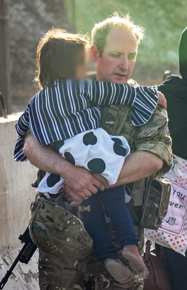 Gazette: EDITORS NOTE IMAGE BLURRED AT SOURCE Handout photo issued by the Ministry of Defence (MoD) of a member of the UK Armed Forces, who continue to take part in the evacuation of entitled personnel, carrying a child at Kabul airport. Issue date: Monday August