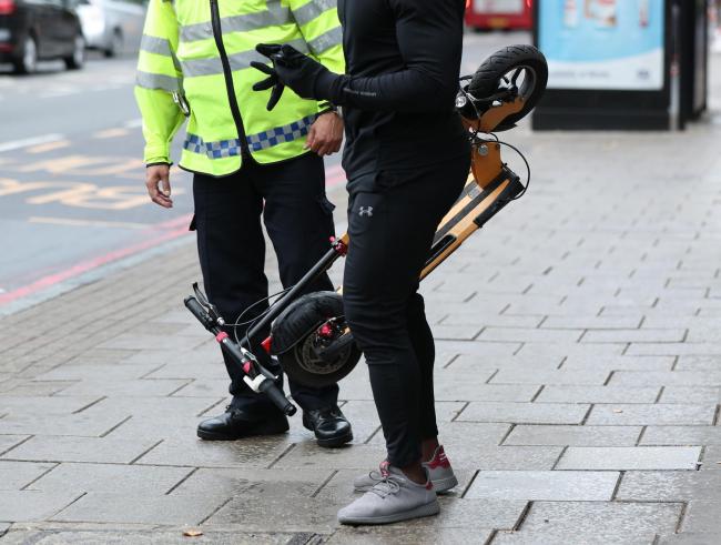 An e-scooter rider is stopped by a police officer