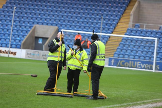 Sinking feeling - Colchester United staff on the JobServe Community Stadium pitch before the Rochdale postponement Picture: STEVE BRADING