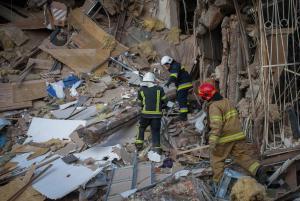 Gazette: Ukrainian firefighters work by a destroyed apartment building in Kharkiv, Ukraine