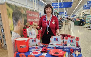 Charity - A volunteer at a Poppy Appeal stall in a Tesco store