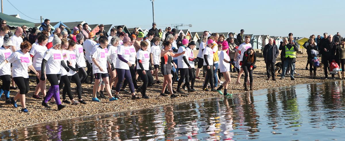 The first few rows of people make a splash in the water as they stride and dip their feet and ankles into the water at Batemans Tower in Brightlingsea